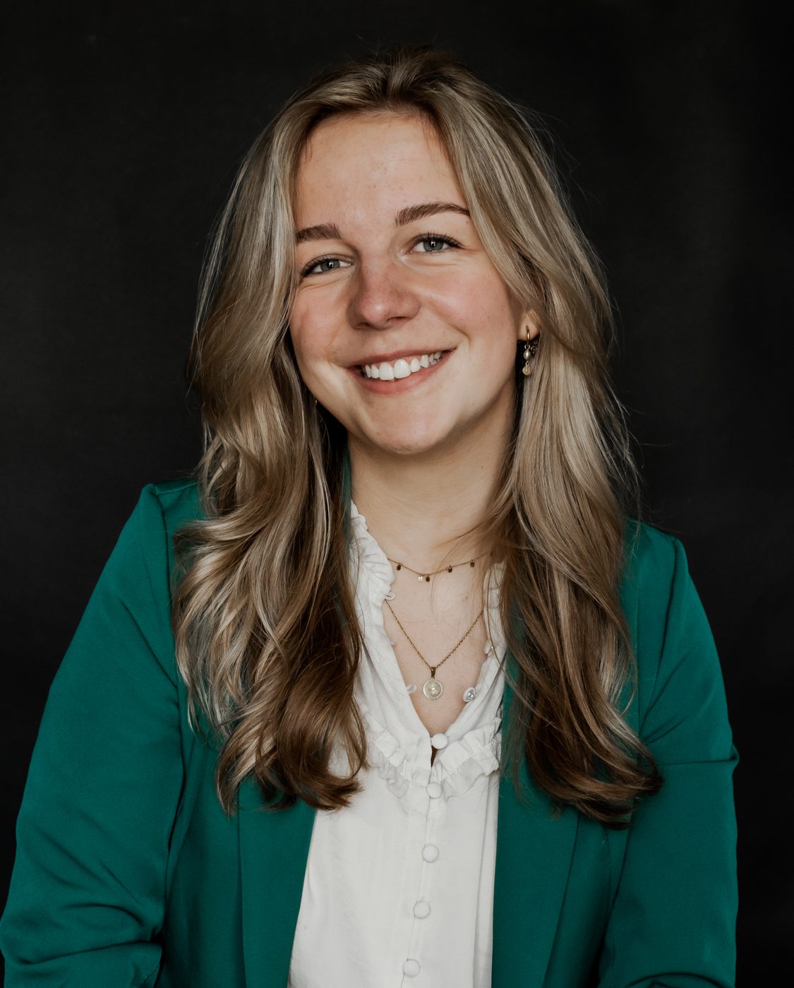 Lotte Witke (@lotteleert) lacht in de camera, in een groene blazer