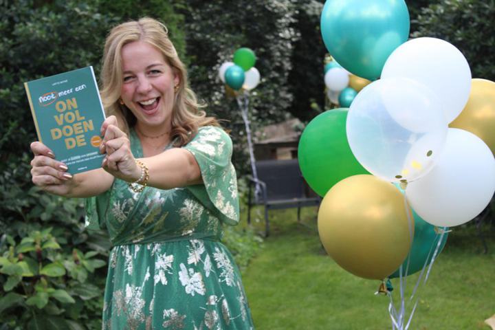 Lotte houdt blij haar boek omhoog tussen de ballonnen